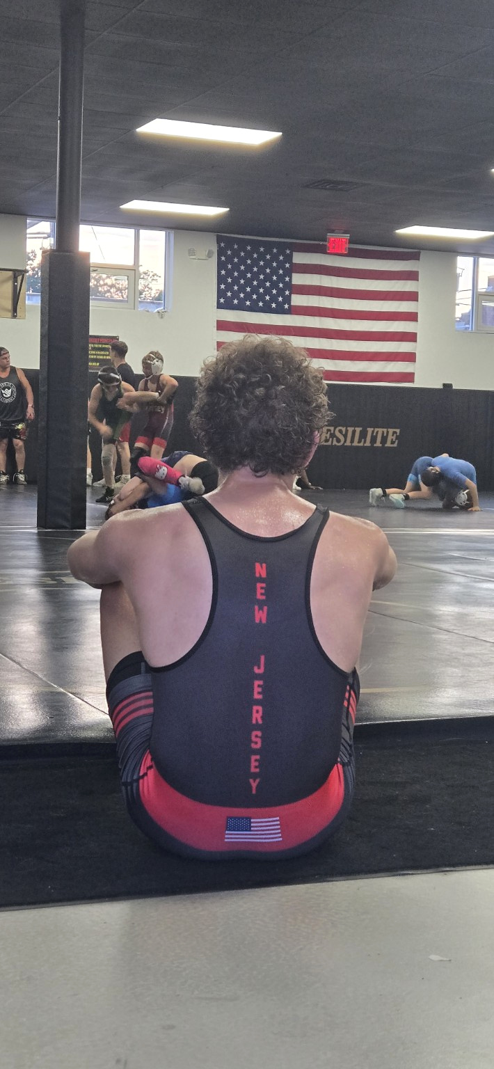 Eden Rodriguez seated at the edge of a wrestling mat after training